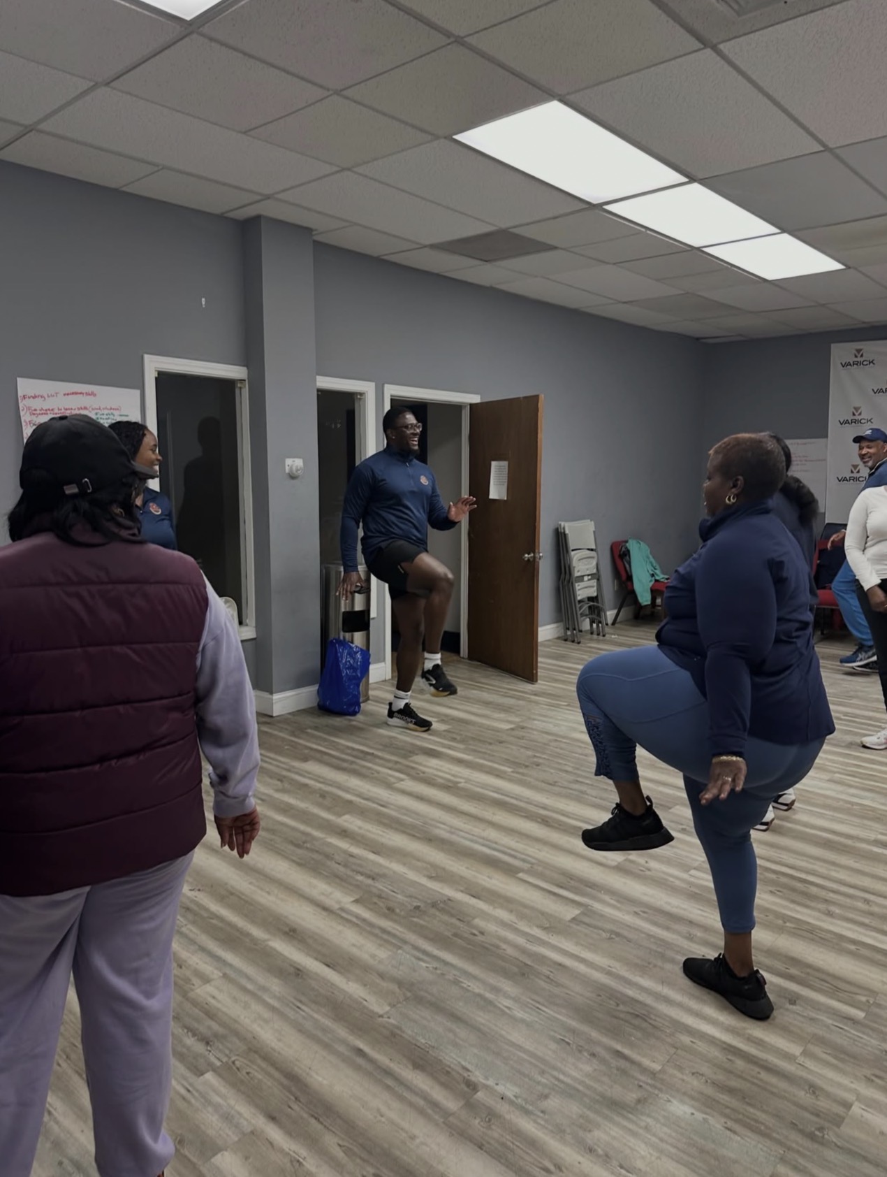 Group members doing a knee-raise exercise together indoors
